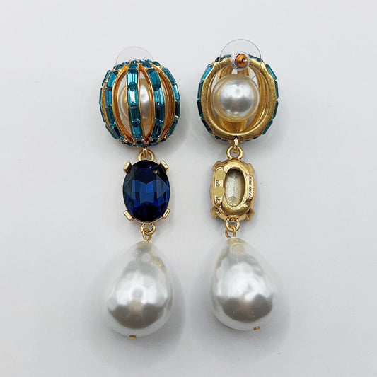 Pair of earrings with pearls and blue gemstones on a light gray background