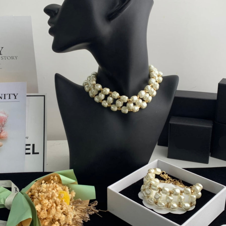 Pearl necklace on a black mannequin bust with Chanel boxes in the background