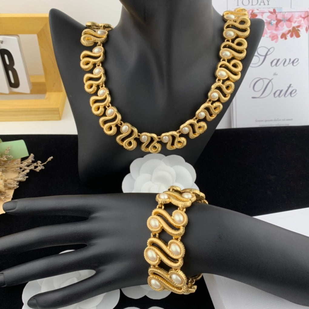 Gold necklace and bracelet set on a black mannequin with a blurred background