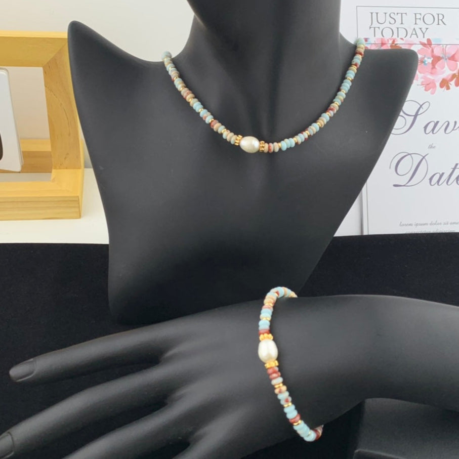 Beaded necklace and bracelet on a mannequin hand with a blurred background